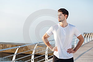 Male athlete standing on pier near the sea