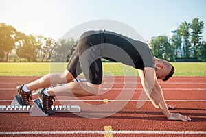 Male athlete on starting position at athletics running track.