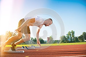 Male athlete on starting position at athletics running track.