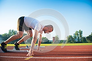 Male athlete on starting position at athletics running track.