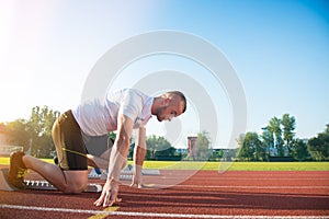 Male athlete on starting position at athletics running track.