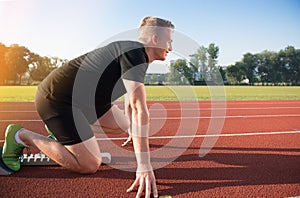 Male athlete on starting position at athletics running track.