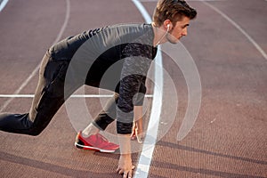 Athlete on starting position at running track. Runner practicing run in stadium racetrack