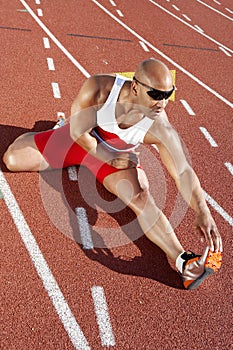 Male Athlete Stretching On Racetrack