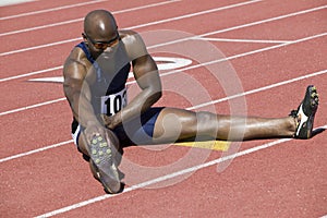 Male Athlete Stretching On Racetrack