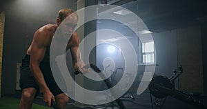 Male athlete working out with ropes in old building. Athlete man in training with ropes near mirror. Battle Rope