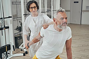 Male athlete working out supervised by an experienced kinesiologist