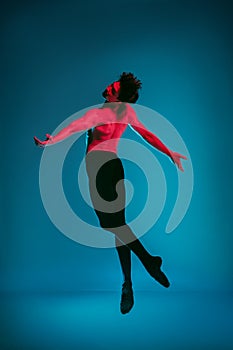 The male athletic ballet dancer performing dance on blue background. Studio shot. Ballet concept. Fit young man