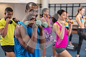 Male athletic exercising with dumbbells in fitness center