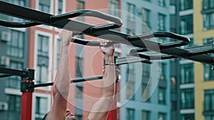 Male athletic latina african man sportsman strong bodybuilder doing pull-ups sport exercises in city outdoor confident