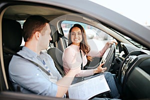 Male auto instructor takes exam in young woman. Practical issue. Cheerful happy and positive student look at teacher and