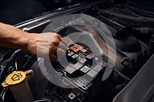 Male auto-mechanic changing relay and checking operation of the fuses