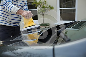 Auto service staff cleaning a car bonnet with rotating wash brush