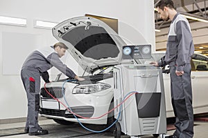 Male automobile mechanics examining car in repair shop