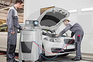 Male automobile mechanics examining car in repair shop