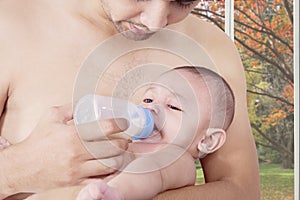 Male baby drinking milk with his father