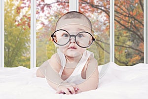 Male baby with glasses lying on bed
