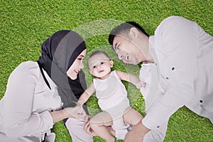 Male baby and parents lying on grass