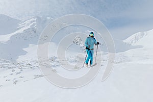 Muž backcountry lyžař pěší na vrchol zasněženého vrcholu v Nízkých Tatrách na Slovensku.