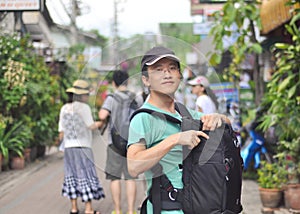 Male backpacker opening camera bag on street