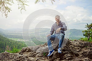 Male resting and enjoying the mountain sitting on rock