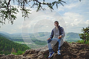 Male resting and enjoying the mountain sitting on rock