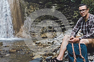 Male Backpacker Sitting On The Rocks Near Waterfall Hiking Destination Experience Lifestyle Concept