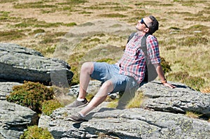 Male backpacker sun bathing on top of the mountain