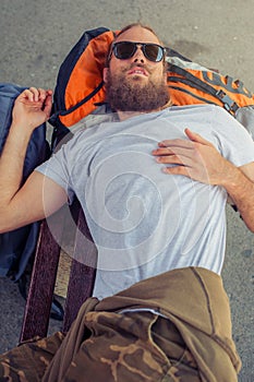 Male backpacker tourist napping on a bench