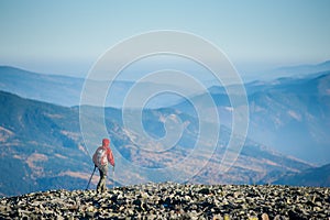 Male backpaker walking on the rocky top of the mountain