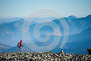 Male backpaker walking on the rocky top of the mountain