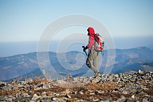 Male backpaker walking on the rocky top of the mountain