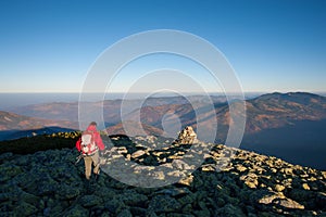 Male backpaker walking on the rocky top of the mountain