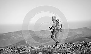 Male backpaker walking on the rocky top of the mountain photo