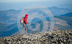 Male backpaker walking on the rocky top of the mountain photo