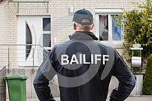 Male Bailiff Standing At House Entrance