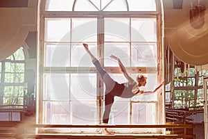 Male ballet dancer is dancing in front of a window