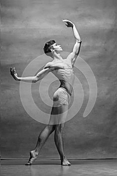 The male ballet dancer posing over gray background