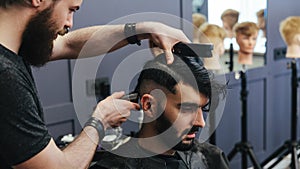 Male barber combing and shaving hair of a male client