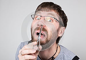 Male barber cuts his own hair in the nose, looking at the camera like the mirror. stylish professional hairdresser