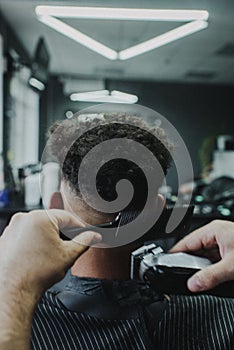 Male barber expertly combs and styles the hair of a customer sitting in a barber chair