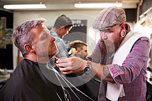 Male Barber Giving Client Shave In Shop