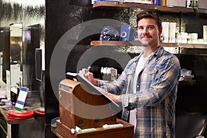 Male Barber Standing By Cash Register Writing Down Booking