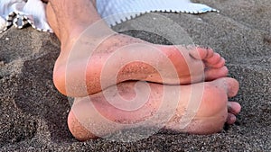 Male bare feet on a sand. Man relaxing on a volcanic black sand beach outdoors. Summer chill on seaside. Film grain