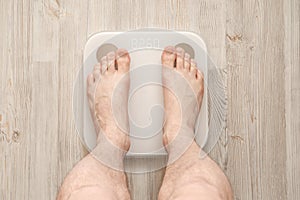 Male bare feet stand on smart scales that makes bioelectric impedance analysis, BIA, body fat measurement. Top view.