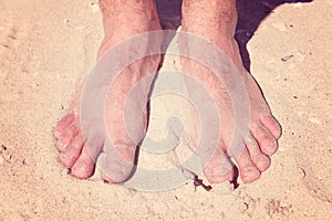 Male bare feet in a warm sand