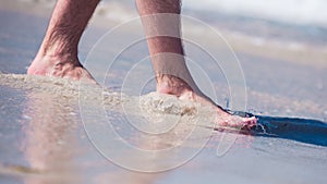 Male bare feet in a warm sand, man taking a walk on a sunny beach with turquoise water