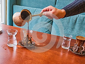 A male barista hand pouring fresh Turkish coffee