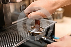 Male barista making espresso using professional coffee