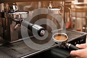 Male barista making espresso using professional coffee machine